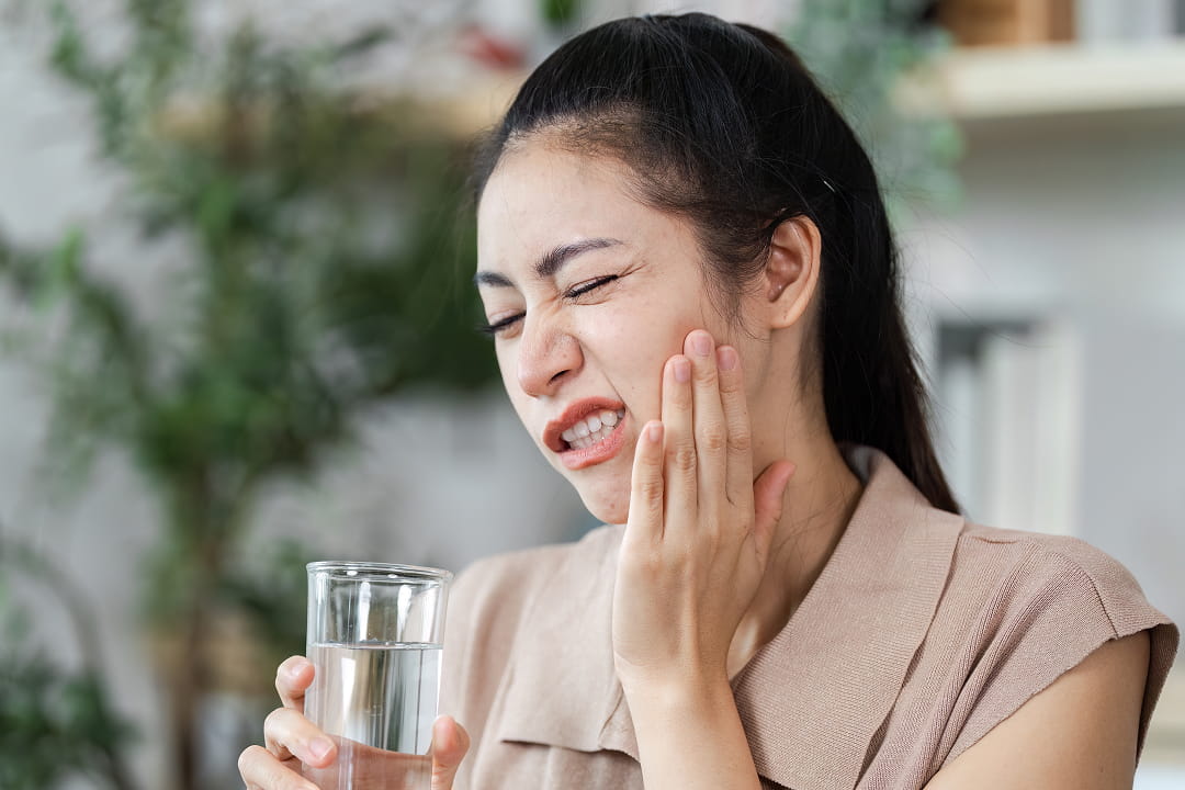 A woman experiencing tooth pain while holding her cheek